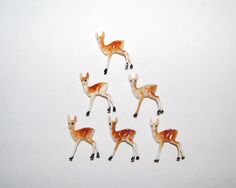 small deer figurines are arranged in the shape of a triangle on a white surface