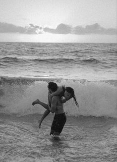 two people are playing in the water at the beach