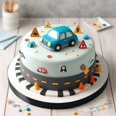 a blue car is on top of a traffic signal cake with other decorations around it