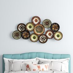 a bed with white sheets and pillows in front of a blue headboard that has decorative plates on the wall above it