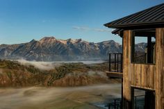 the mountains are covered in fog and low lying clouds as seen from an elevated deck