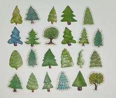 a bunch of trees that are painted in different colors and shapes, all sitting on a white surface