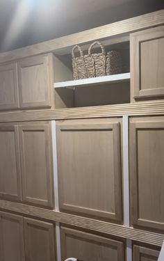 an empty closet with wooden cabinets and baskets