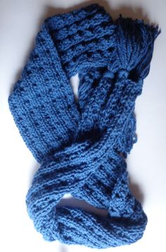 a blue knitted scarf laying on top of a white table