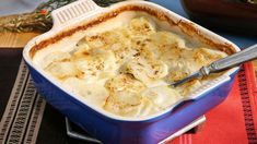 a blue casserole dish filled with mashed potatoes and topped with gravy