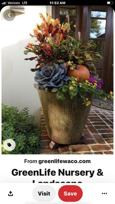 a large potted planter filled with flowers and pumpkins sitting on a brick walkway