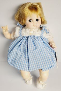 a doll with blonde hair wearing a blue checkered dress and holding a knife in her hand