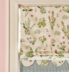 a window with a flowered valance hanging from it's side next to a window sill