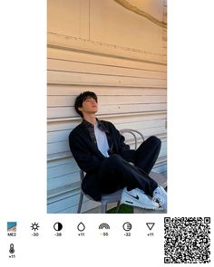 a man sitting on top of a metal chair next to a white wall with qr code