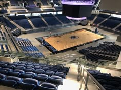 an empty basketball court in the middle of a large arena with rows of blue seats