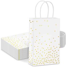 a white paper bag with gold dots on the front and side, sitting next to each other