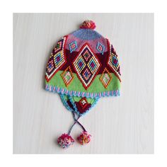 a colorful knitted hat with tassels and pom poms sits on a white surface