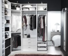 a white closet filled with lots of clothes and drawers next to a bed on top of a rug