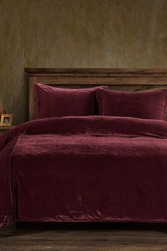 a bed with a maroon comforter and pillows