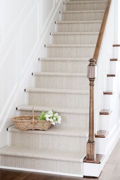 a basket with flowers sitting on the bottom of some stairs next to a banister