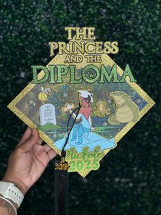 the princess and the frog diploma is being held by a person's hand in front of a green wall