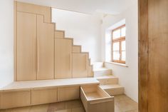 an empty room with stairs and cabinets in the corner, next to a large window