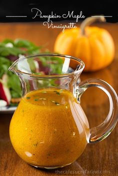 a glass pitcher filled with liquid sitting on top of a wooden table next to vegetables