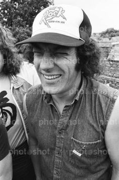 black and white photo of two people smiling for the camera, one man is wearing a hat