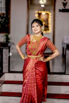 a woman in a red and gold sari standing with her hands on her hips