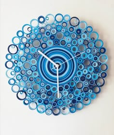 a clock made out of blue and white circles on a white wall with black hands