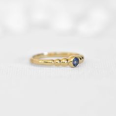 a yellow gold ring with two blue stones on the side, sitting on a white surface