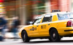 a yellow taxi cab is driving down the street