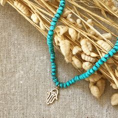 Turquoise is called the self acceptance stone. It promoted self-esteem and unconditional love. Our hand beaded necklace also has a Hamsa charm pendant in goldtone plated brass with cubic zirconia stones. The Hamsa symbol dates back to ancient Mesopotamia where the open right hand is seen in artifacts and in the amulets of the goddess Ishtar. Other symbols of divine protection based around the hand include the Hand-of-Venus which was used to protect women from the evil eye and/or boost fertility, Turquoise Polished Beads Necklace For Gift, Healing Howlite Turquoise Jewelry, Healing Turquoise Howlite Jewelry, Turquoise Polished Beads Jewelry For Healing, Turquoise Spiritual Necklaces With 8mm Beads, Adjustable Turquoise Pendant Necklace With Spiritual Style, Adjustable Spiritual Turquoise Pendant Necklace, Turquoise Necklace With Polished Beads As Gift, Turquoise Beaded Necklace With Natural Stones For Gift