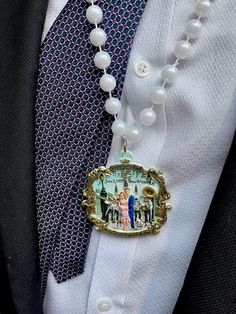 a close up of a person wearing a suit and tie with a necklace on it