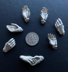 six plastic hands are arranged in a circle on a table next to a quarter penny