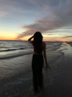 a woman standing on top of a beach next to the ocean