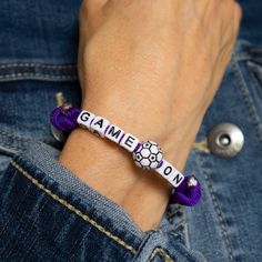 a person wearing a purple bracelet with soccer balls on it and the word game on