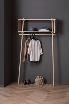 a coat rack with clothes and shoes hanging on it next to a pair of shoes