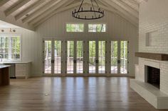 an empty living room with wood floors and white painted walls, large open doors leading to the kitchen