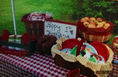 an outdoor birthday party with apples in baskets and other items on a picnic table outside