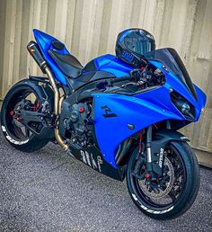 a blue motorcycle parked next to a wall