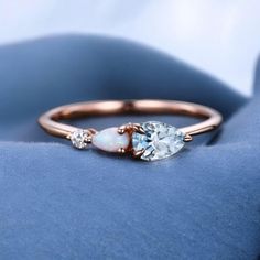 an opal and diamond engagement ring on a blue velvet surface, with two diamonds in the middle