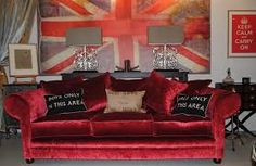 a living room with red velvet couches and british flag wall art on the walls