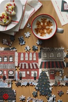 a cup of coffee is sitting on a table next to some puzzles and cookies