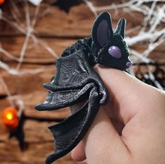 a hand holding a black bat shaped ring