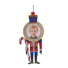 a christmas ornament with a boy in a nutcracker outfit holding a candy cane