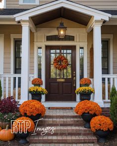 a front porch with pumpkins and flowers in large planters next to the door