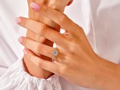 a woman's hands holding an engagement ring with a diamond in it and the other hand on her chest