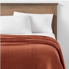 a bed with two pillows and an orange blanket