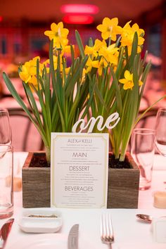 the table is set with yellow flowers and place cards for guests to sit down at