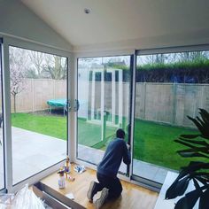 a man is painting the inside of a room with sliding glass doors that look out onto a back yard