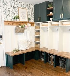 an organized mud room with green cabinets and white linens on the shelves, along with baskets