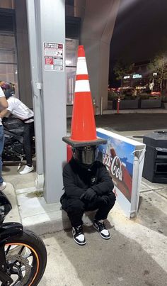 a man sitting on the ground wearing a cone hat