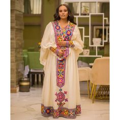 This stunning Habesha Kemis is truly fit for a queen, crafted from the finest Menen fabric and adorned with exquisite Tilf detailing that is sure to take your breath away. The Shimena dress is sleek and sophisticated, with a fitted bodice and a flowing skirt that moves with grace and elegance. The Menen fabric is soft and sumptuous, with a rich texture that adds depth and dimension to the overall look. The Shimena cut is timeless and classic, with a flattering shape that accentuates the curves o Eritrean Dress, Ethiopian Clothing, Habesha Dress, Ethiopian Dress, Habesha Kemis, Regal Elegance, Flowing Skirt, Rich Textures, Fitted Bodice