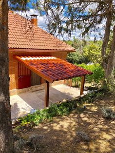 the house is surrounded by pine trees and has a red roof with white tiles on it